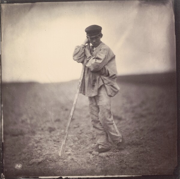 Unknown, [Boy leaning on staff in field]