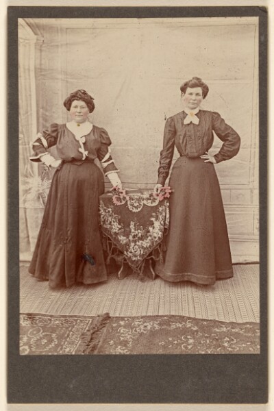 Unknown, [Two women standing at a table holding flowers]