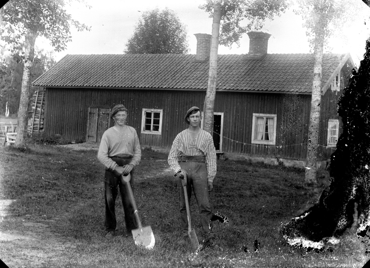Gustaf Ferdinand Hallberg, Två män med spadar. Ekonomibyggnad i bakgrunden.