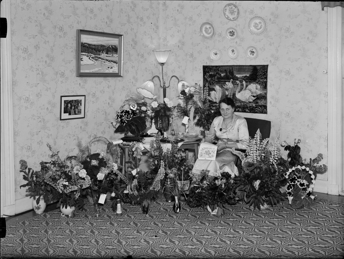 Skötsner-Edhlund, Kvinna i hemmiljö omgiven av blommor, Östhammar, Uppland