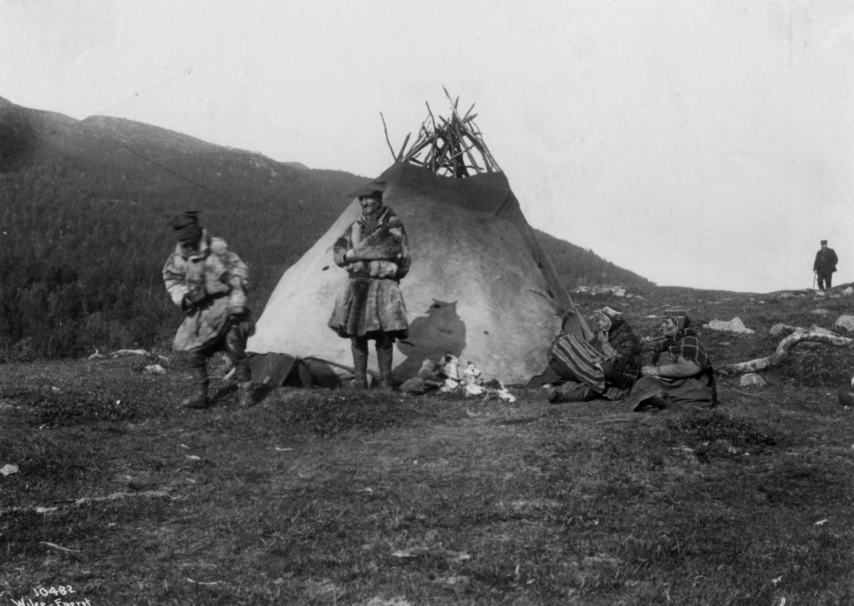 Anders Beer Wilse, Svenske samer utenfor et telt. En mann med stokk i bakgrunnen. Antagelig Lyngseidet 1909.