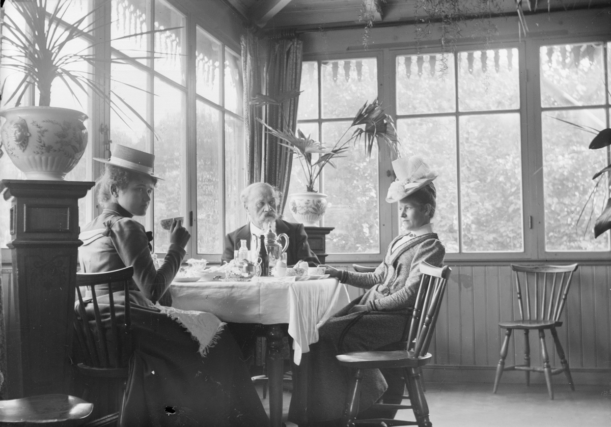 Henri Osti's Fotografiateliér, Sällskap vid frukostbord, sannolikt Ostis ateljé, Uppsala före 1914