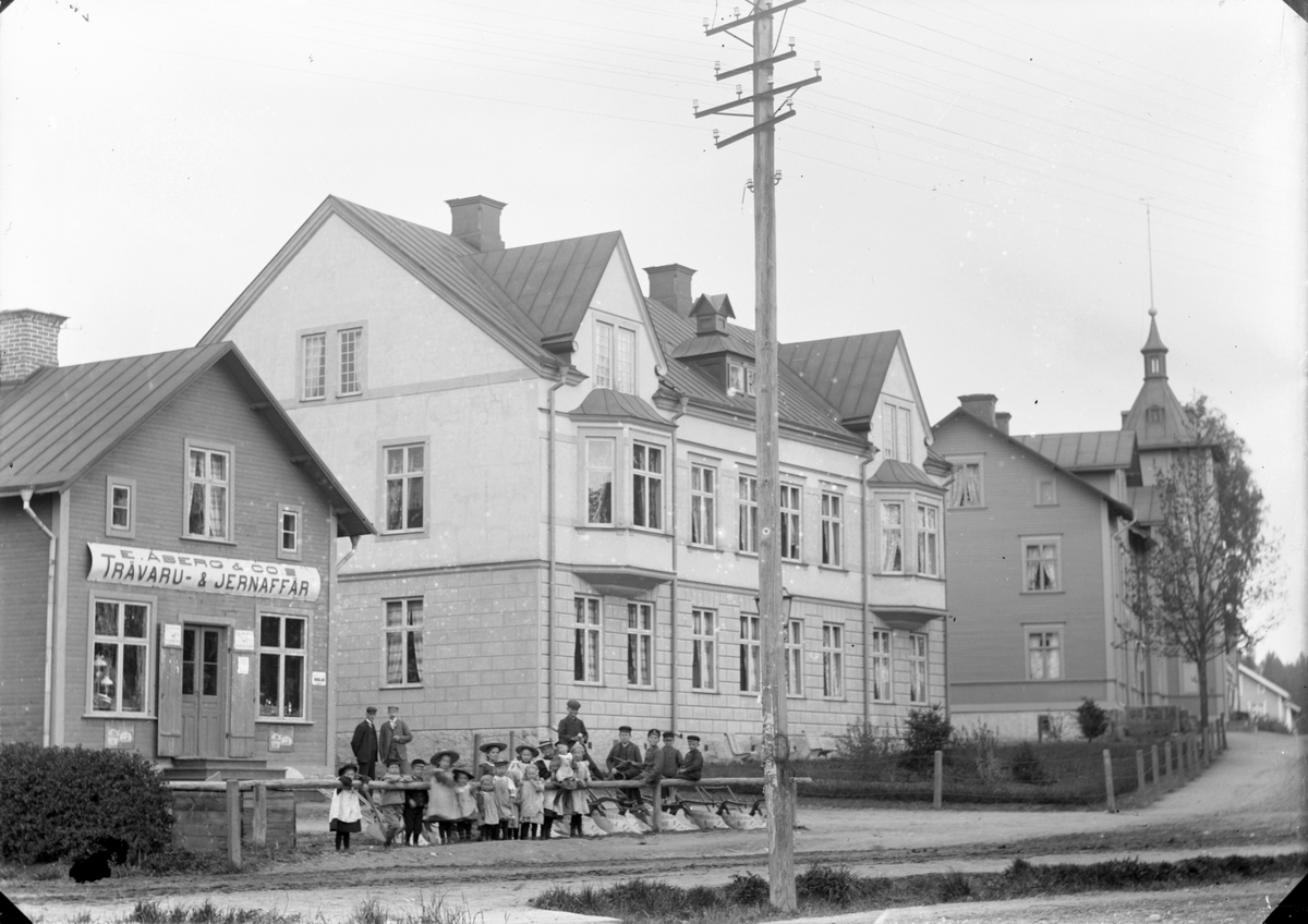 Gustaf Ferdinand Hallberg, E. Åberg & Co, trävaru- & jernaffär, exteriör. Bostadshus. Barngrupp.