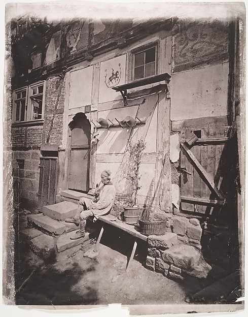 Unknown, [Man Smoking Pipe Outside His Home on Village Street]