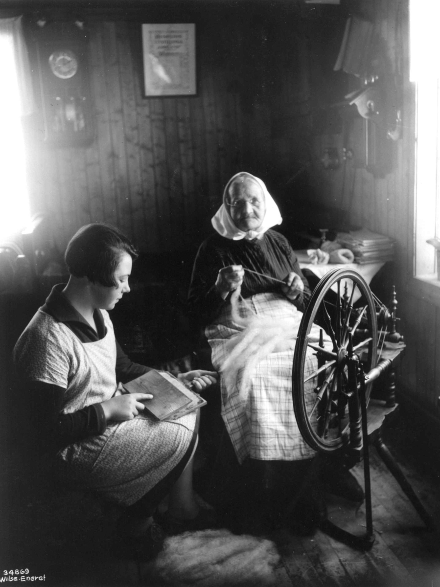 Anders Beer Wilse, To kvinner sitter i en stue og karder og spinner, 1929.