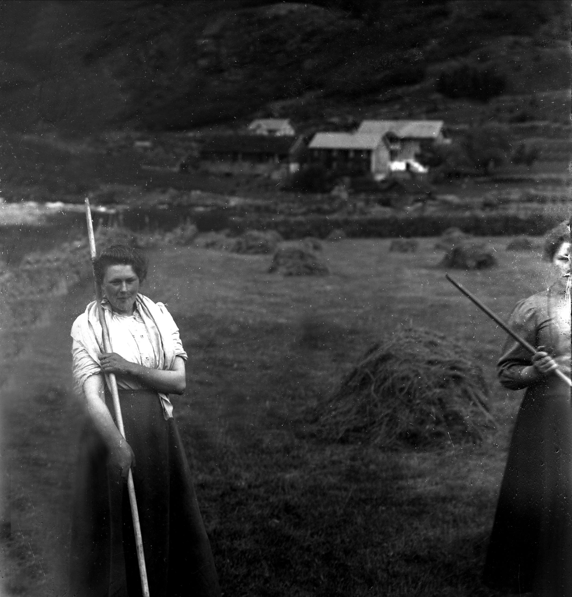 Gustav Borgen, Høyonn, to kvinner raker høy. Brudepike Hegg,Valdres.