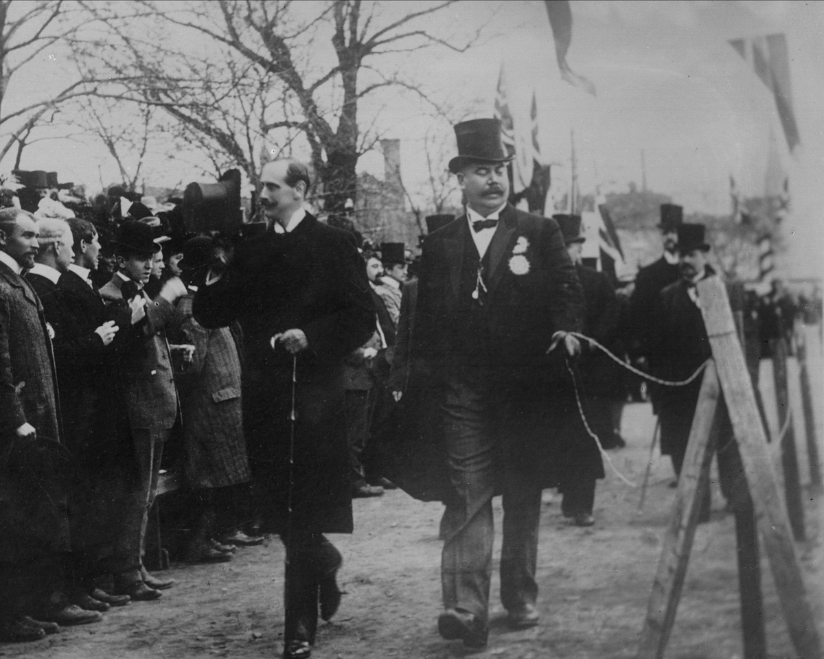 Gustav Borgen, Avfotografering. Gruppeportrett, kong Haakon VII hilser tilskuere med hatten.