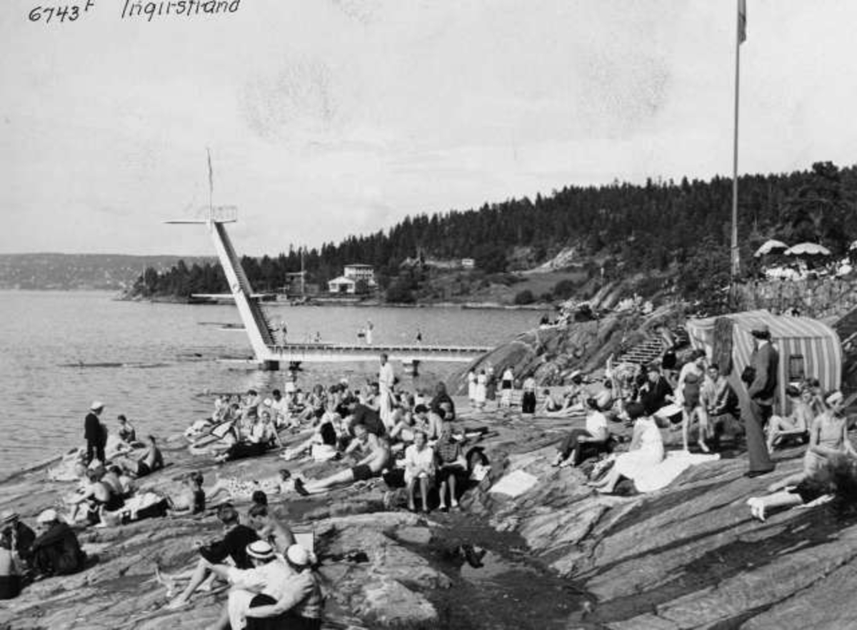 Anders Beer Wilse, Strandliv med badegjester som soler seg på svaberget ved sjøen på Ingierstrand bad utenfor Oslo. Stupetårn i bakgrunnen.