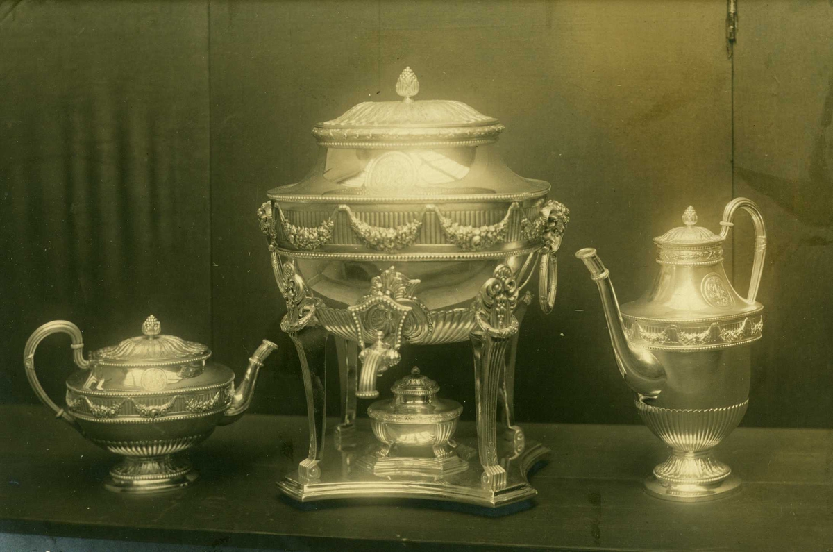 Anders Beer Wilse, Temaskin, kaffekanne og tekanne i sølv. Del av Trondhjems damers kroningsgave. Utført i 1906 av J. Smedja, Christensen & Svendsen, Trondheim. Fotografert 1908.