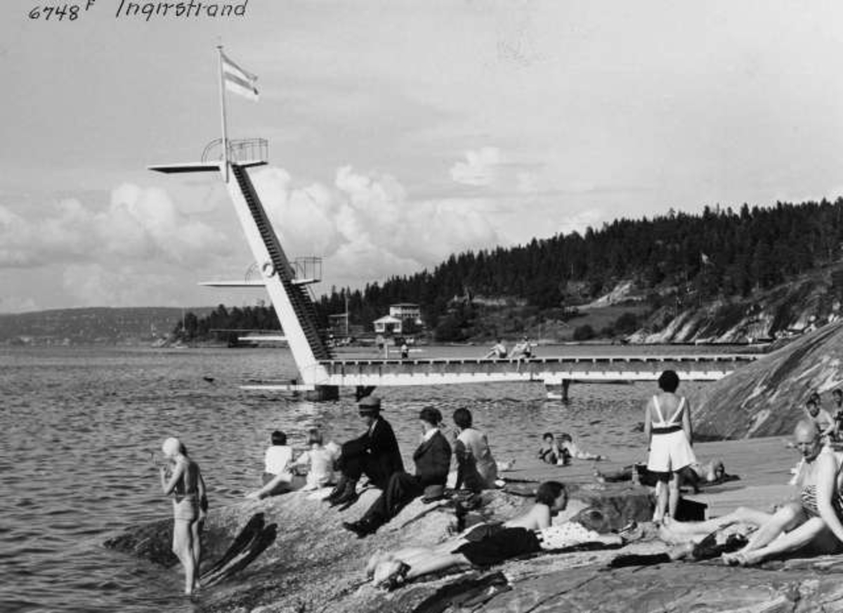 Anders Beer Wilse, Strandliv med badegjester som soler seg på svaberget ved sjøen på Ingierstrand bad utenfor Oslo. Stupetårn i bakgrunnen.