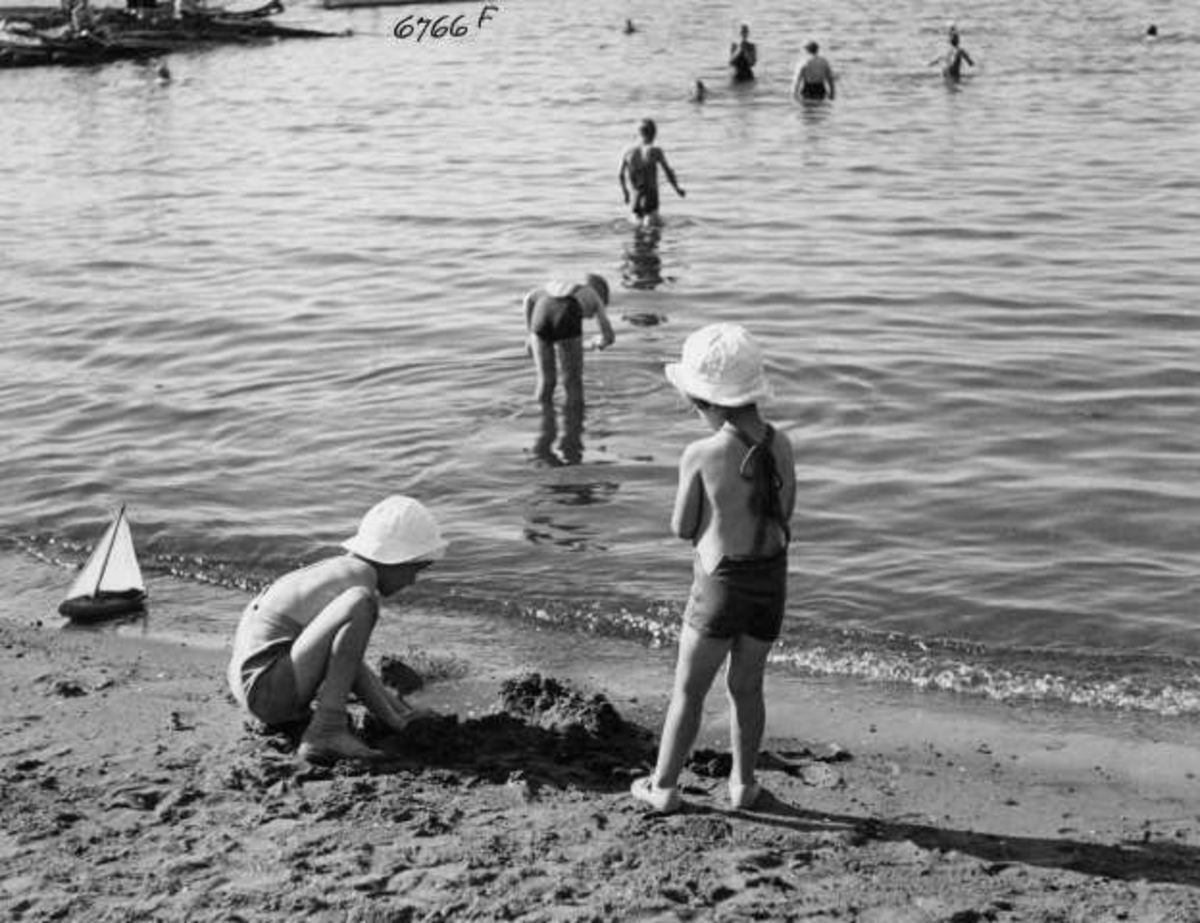 Anders Beer Wilse, Strandliv med badegjester ved sjøen på Ingierstrand bad utenfor Oslo. Barn leker i sanden.