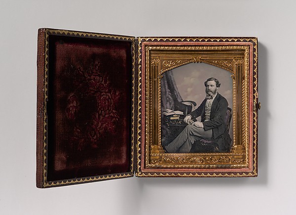 Unknown, [Man Seated in Front of Cloud Backdrop, Books and Top Hat on Table]