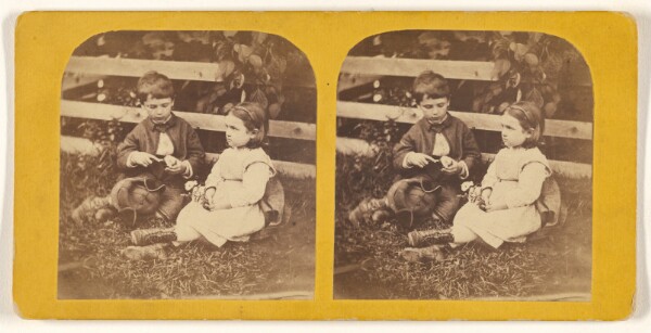 Unknown, [Little boy and girl posed on grass near fence]