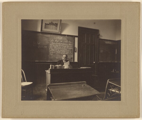 Unknown, [Portrait of a male mathematics teacher with moustache seated at his classroom desk]