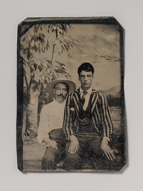Unknown, [Young Man in a Striped Jacket, Sitting on the Lap of Another Man in Front of Painted Outdoor Backdrop]