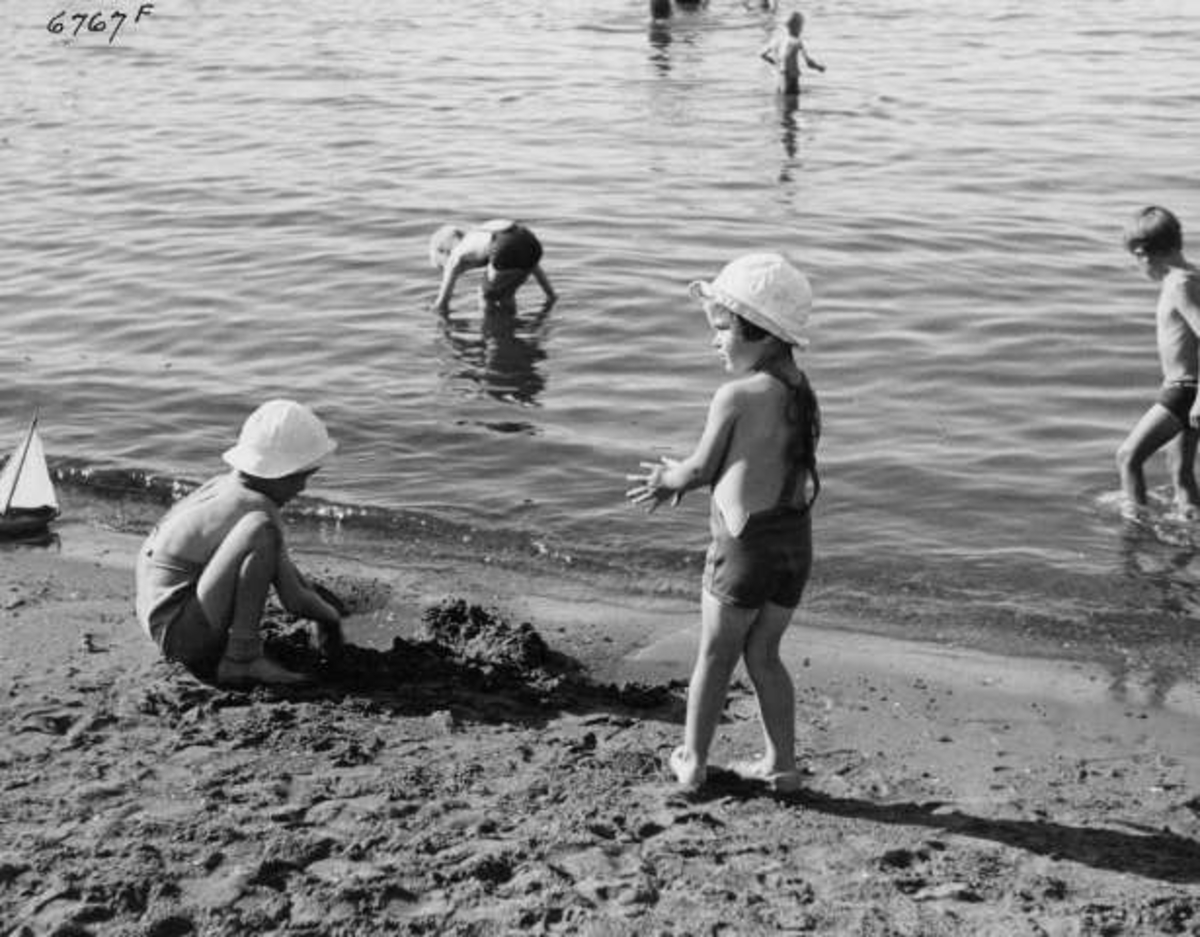 Anders Beer Wilse, Strandliv med badegjester ved sjøen på Ingierstrand bad utenfor Oslo. Barn leker i sanden.