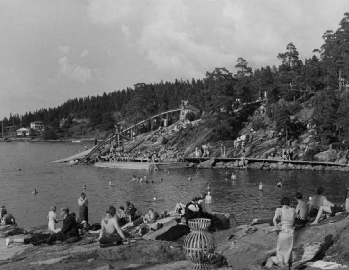 Anders Beer Wilse, Strandliv med badegjester som soler seg på svaberget ved sjøen på Ingierstrand bad utenfor Oslo. Vannsklie i bakgrunnen