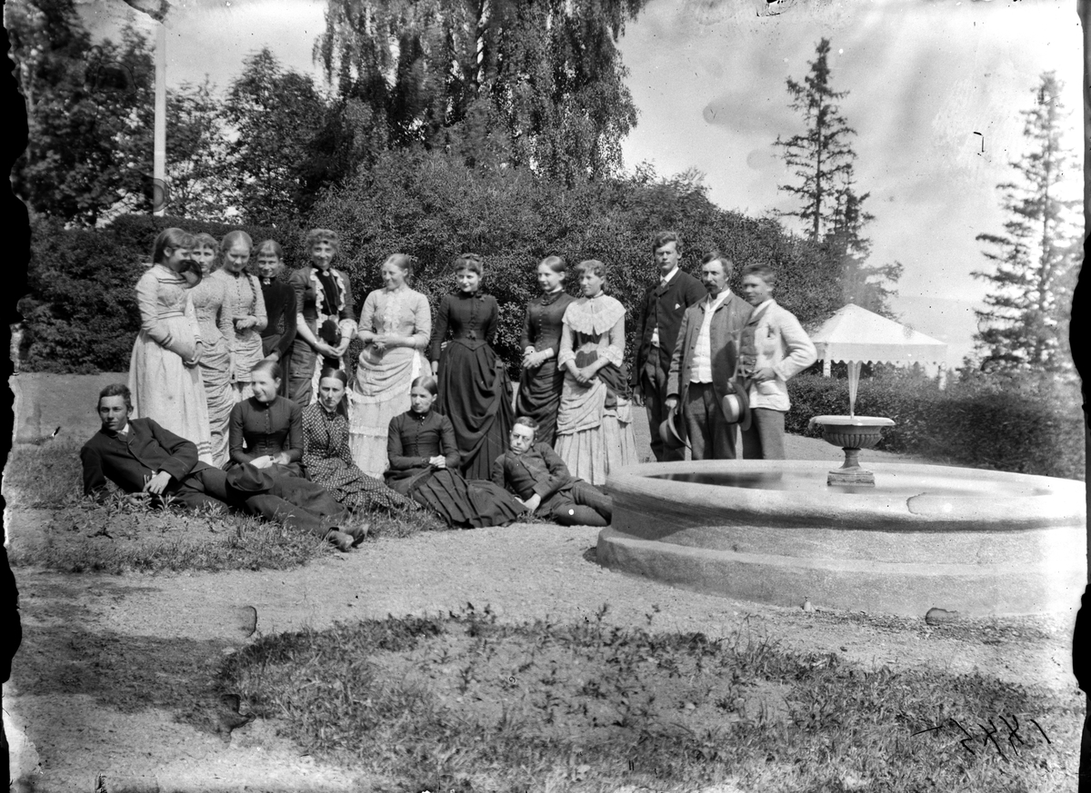 Jacob Tollesen Hoel, Hovinsholm gård, Helgøya i Ringsaker. Familiegruppe Hoel ved springvannet, fontenen. Ukjente navn. Foto Jacob Hoel 1885.