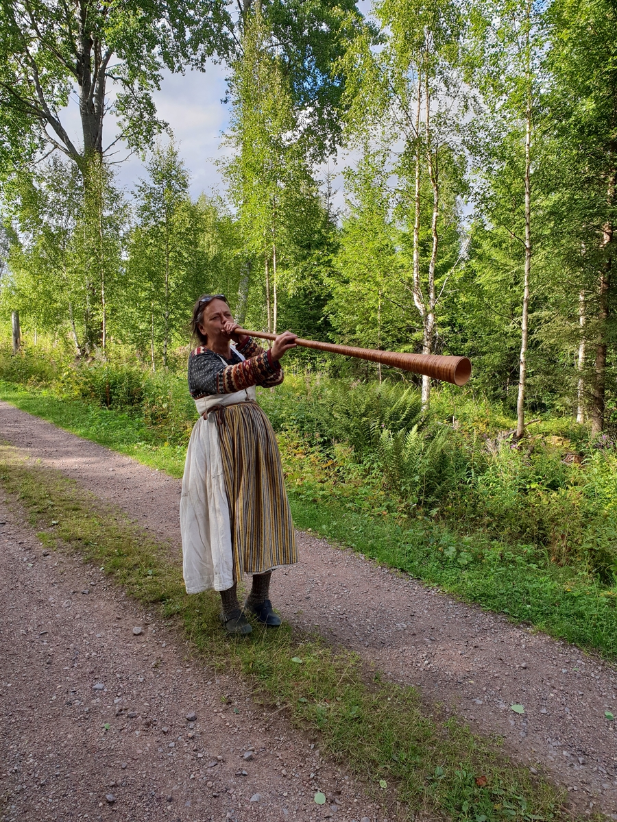 Jennie Tiderman-Österberg, Yvonne Smedberg plays a fist door to lure the cows home in the evening, Kättboåsen, Venjan, Mora, 2018.