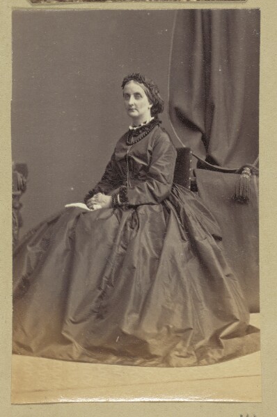 Unknown, [Portrait of woman standing next to table and plant]
