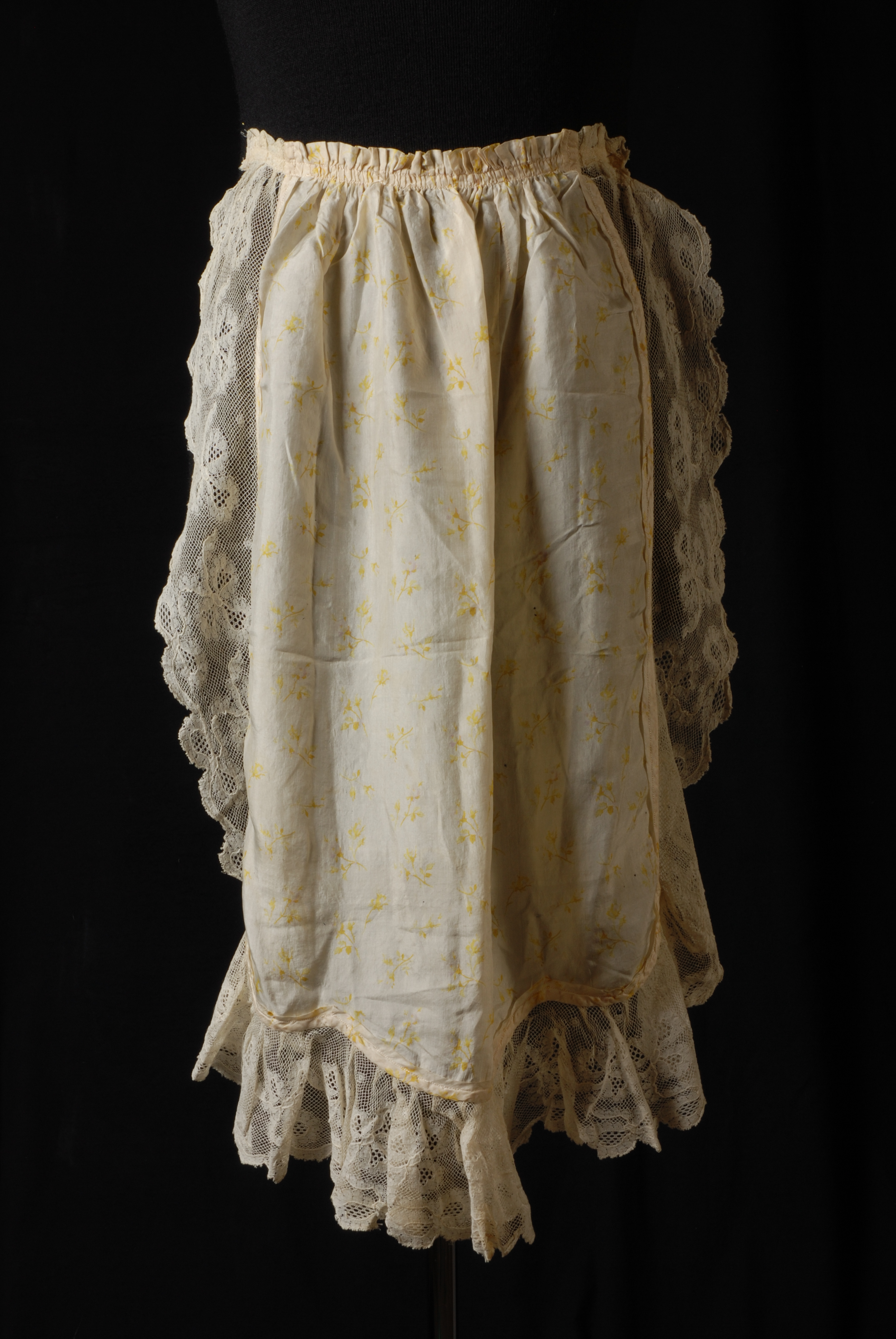 Unknown artist, Lichtgeel schort met bloempatroon en een brede bies van kant